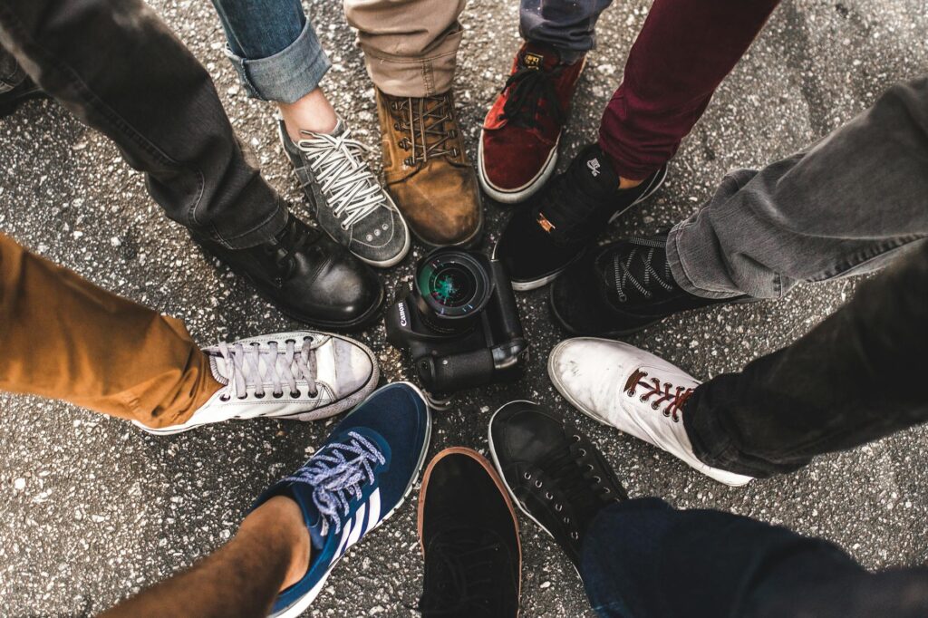 pexels-photo-573315-573315 Top-down view of various sneakers encircling a DSLR camera on pavement.
